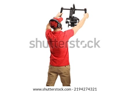 Rear view shot of a camera operator using a camera gimbal stabilizer isolated on white background Royalty-Free Stock Photo #2194274321