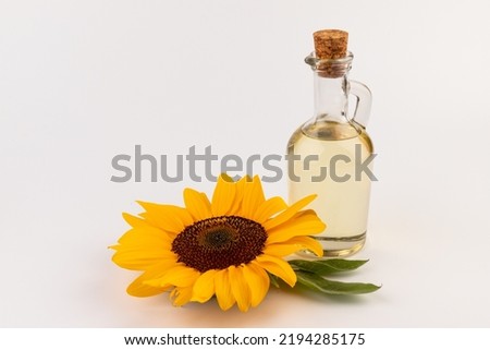 Sunflower, jug of oil and seeds on white background