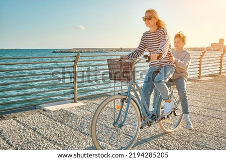 Happy family, Carefree mother and son with bike riding on beach having fun, on the seaside promenade on a summer day, enjoying vacation. Togetherness Friendly concept Royalty-Free Stock Photo #2194285205