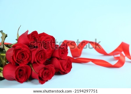 Beautiful red roses and ribbons on light blue background, space for text. St. Valentine's day celebration