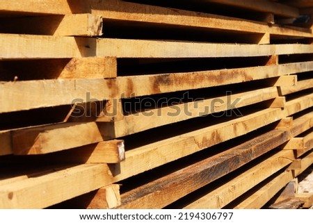 Wooden boards close up. Lots of boards stacked on top of each other in a warehouse. Perspective angle of wooden boards close-up in a lumber warehouse.