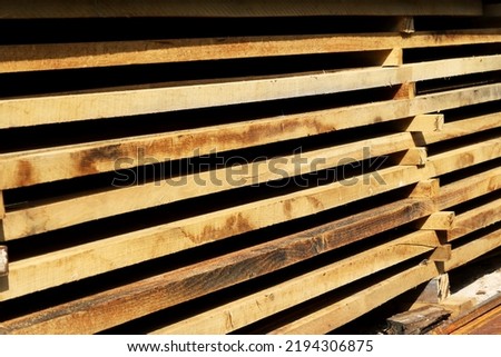 Wooden boards close up. Lots of boards stacked on top of each other in a warehouse. Perspective angle of wooden boards close-up in a lumber warehouse