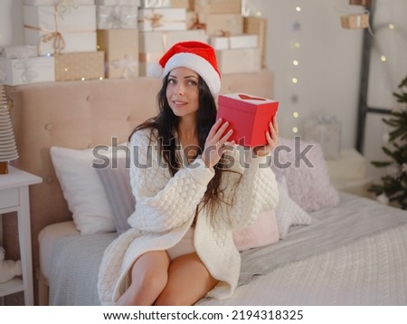 Cute woman in santa hat opening christmas present red box. celebration and people concept. Merry Christmas, Happy Holidays.
