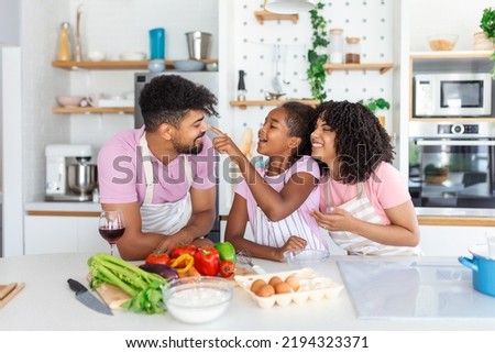 Overjoyed young family with Daughter have fun cooking baking pastry or pie at home together, happy smiling parents enjoy weekend play with child doing bakery cooking in kitchen