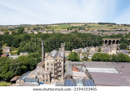 Aerial photo of the historic Yorkshire town of Huddersfield in the UK, showing the residential housing estates alone side victorian historical factories on a sunny day in the summer time