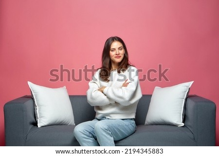 Confident proud pleased young girl sitting on modern comfortable sofa couch with crossed arms, looking at camera smiling Royalty-Free Stock Photo #2194345883