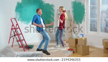 Cute positive Caucasian young happy couple dancing and moving in room during home renovation process, wife and husband smiling and dance, having fun together in new apartment, repair concept Royalty-Free Stock Photo #2194346355