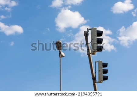 A low angle shot of traffic lights on horizontal pole and street lamp against blue cloudy sky background