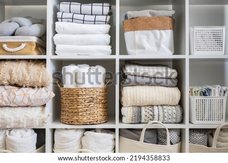 Bed linens closet neatly arrangement on shelves with copy space domestic textile Nordic minimalism comfortable storage. Rolled towels in straw basket duvet cover sheet pillow plaid in cupboard Royalty-Free Stock Photo #2194358833