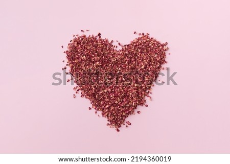 Dried red rose petals in shape of heart.