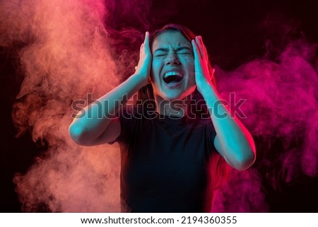 Emotional pain. Young dark hair woman shouting isolated over pink background with clouds of smoke. Concept of mental health, art, human emotions, challenges, ad Royalty-Free Stock Photo #2194360355