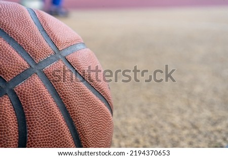 Orange basketball ball on the ground. Close-up ball on the red court. Basketball on the street or indoor court. Sports gear without people. Minimalism. Template, sport background	