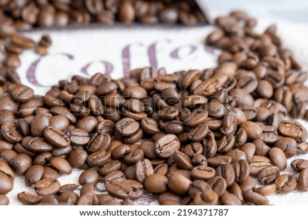 scattered coffee beans on a table, next to word coffee, coffee culture, Space for text. Good picture for cover, calendar, postcard, wallpaper, background, product, website, blog, business, magazine