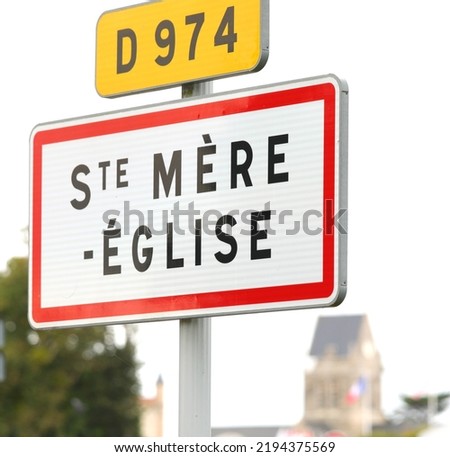 sign with the words STE MERE EGLISE indicating a place of the D-DAY D-DAY landing in WWII and the bell tower in the background