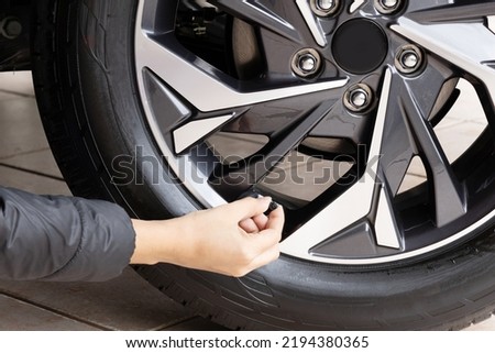 Person calibrating car tire - closeup on hand Royalty-Free Stock Photo #2194380365