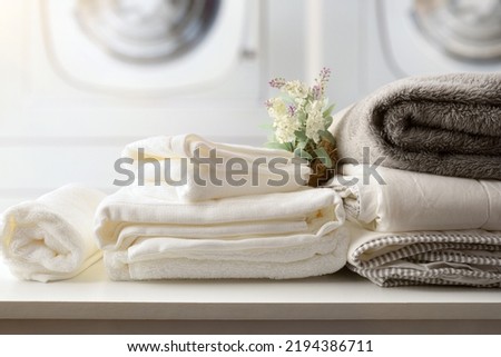 Self-service laundry for the public with bedding and staff on a white bench and professional washing machines in the background. Front view. Horizontal composition. Royalty-Free Stock Photo #2194386711