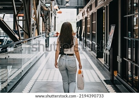 Modern Latina young woman walking in large modern mall. Young pretty brunette female consumer