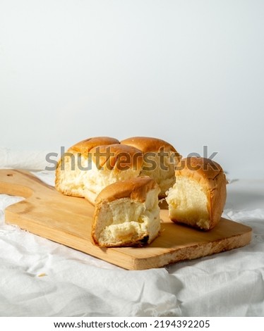 pull off bread (roti sobek in Indonesian), with white patchwork table mat and wooden cutting board - white background Royalty-Free Stock Photo #2194392205