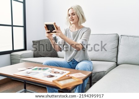 Young caucasian woman smiling confident decoring with frame at home
