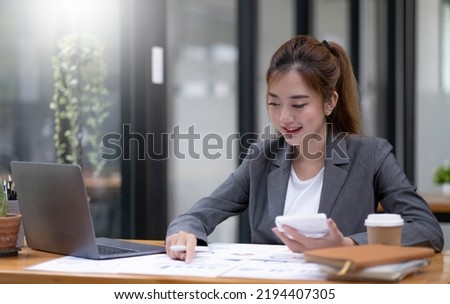 Pretty and charming asian businesswoman sitting happily smiling with laptop computer in the office.
