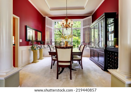 Luxury dining room with bright red wall and white french window.