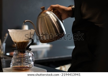 Coffee shop worker standing at the counter with hand drip coffee set background