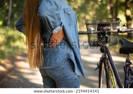 back pain, cramps after cycling girl in jeans. High quality photo