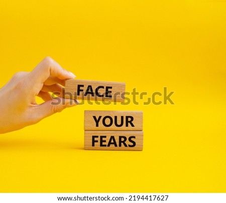 Face your Fears symbol. Wooden blocks with words Face your Fears. Beautiful yellow background. Businessman hand. Business and Face your Fears. Copy space.