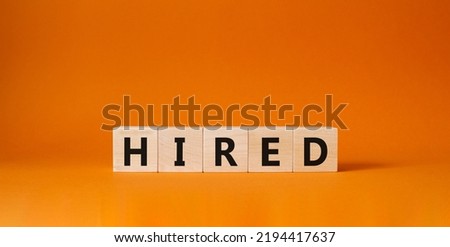 Hired symbol. Wooden cubes with word Hired. Beautiful orange background. Hired concept. Copy space.