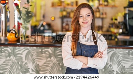 Young caucasian woman waitress smiling confident standing with arms crossed gesture at restaurant
