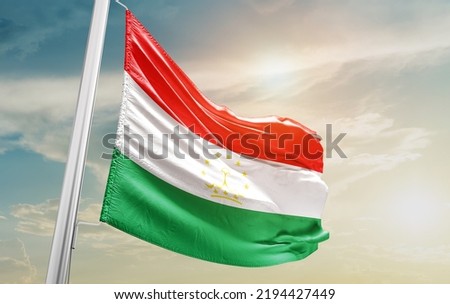 Tajikistan national flag waving in beautiful clouds.