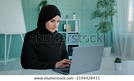 Busy Islam businesswoman in black hijab freelancer Islamic Arabian girl student worker Muslim woman female with laptop working e-learning typing online chat e-commerce app web browsing in network Royalty-Free Stock Photo #2194428411