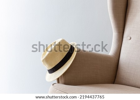 sun hat lies on the handle of the arm chair