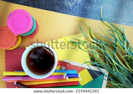 Outdoor photo of art working dekstop with colored felt pens, cup of coffee and paints, flat lay top view
