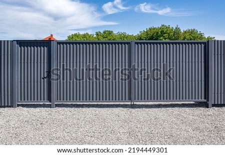 Iron gates from a profiled sheet on the site. Royalty-Free Stock Photo #2194449301