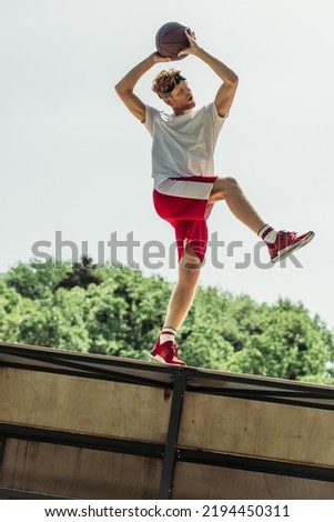low angle view of sportive man playing basketball outdoors in summer