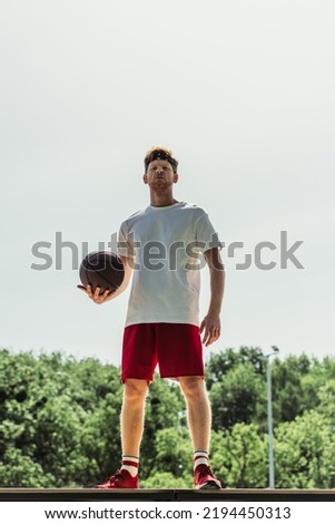 full length of young basketball player in sportswear standing with ball outdoors