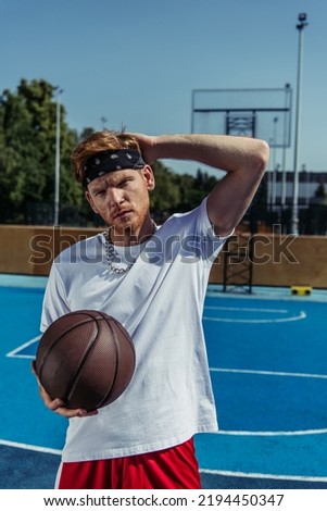 redhead sportsman in bandana holding ball and looking at camera