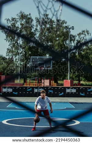 full length of basketball player training on modern court on blurred foreground