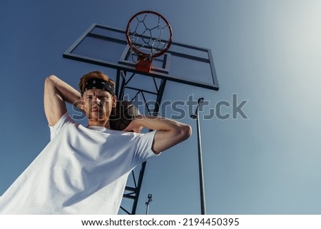 low angle view of young sportsman looking at camera under basketball hoop
