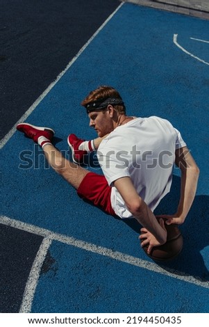 top view of redhead basketball player sitting on court near ball