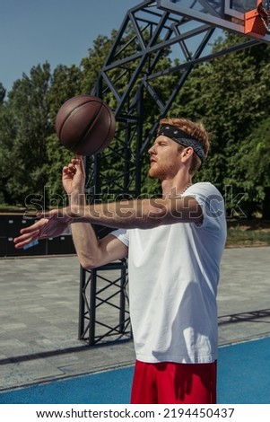 young basketball player in white t-shirt spinning ball on finger outdoors