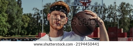 redhead basketball player in headband holding ball and looking at camera, banner