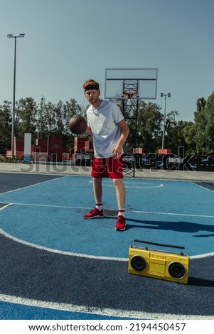 full length of basketball player standing on court near boombox