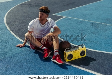 basketball player in red sneakers and bandana sitting on court near boombox