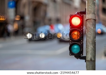 city crossing with a semaphore on blurred background with cars in the evening streets, red light