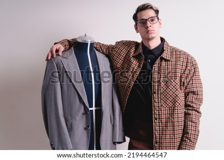 Clothes designer with mannequin. Man dressed in a suit and glasses who is a fashion designer. Fashion designer in a gray suit that he made. High quality photo
