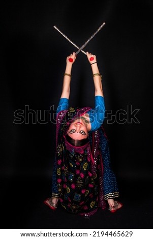 Beautiful Indian dancer in bright traditional clothes in the pose of Indian dance on a black background. Indian classical dance 