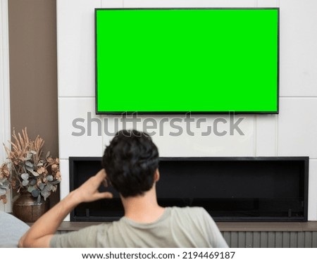 Man sitting on the couch and watching tv. Green screen concept