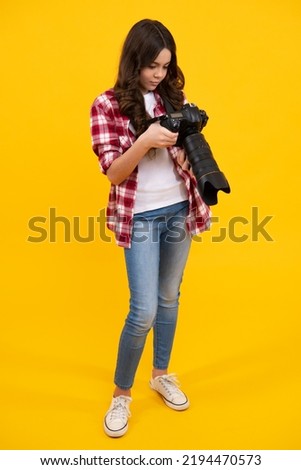 Teenager lifestyle, teen hipster hold professional camera. Girl with photo camera photographing, isolated on studio background.